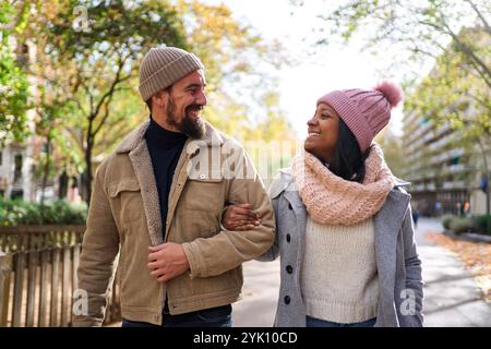 Multiracial couple walking outside talking and looking at each other with complicity and love. Stock Photo
