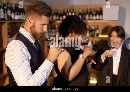 High angle shot of mixed race sommeliers scenting aromatic wine while having glasses in hands Stock Photo