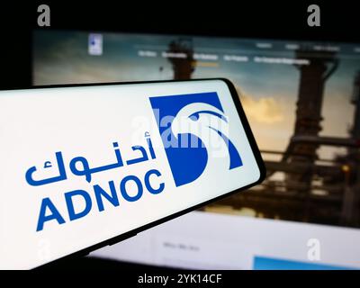 In this photo illustration, a smartphone with the logo of oil business Abu Dhabi National Oil Company (ADNOC) is seen in front of business website. Stock Photo