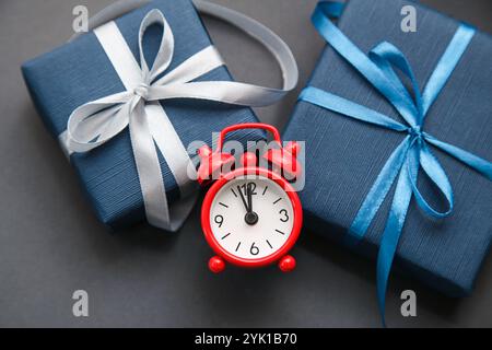 Red Alarm Clock, Dark Blue Gift box on grey background. Gift of Time. Gift for men. Fathers day. Present for him. Stock Photo