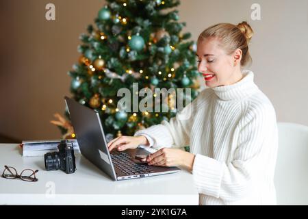 Smiling woman employee working in office with documents and laptop during Christmas time Stock Photo