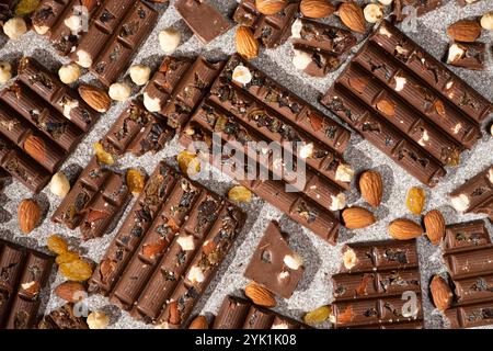Broken chocolate pieces with nuts and raisins on a stone background top view Stock Photo