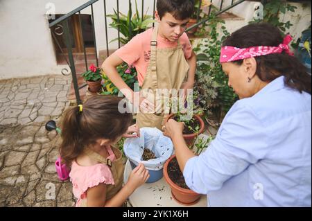 A family of three, including a mother and two children, engages in gardening together. They are planting flowers in pots, enjoying this bonding activi Stock Photo