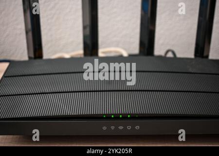 Black wireless router with multiple antennas providing fast internet access, featuring signal strength indicator lights. Stock Photo