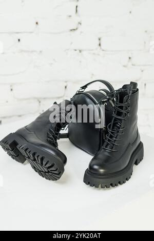 Women's black leather boots and a black leather backpack stand on a white background. Women's fashion Stock Photo
