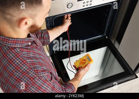 Repairman testing oven element with multimeter, closeup Stock Photo