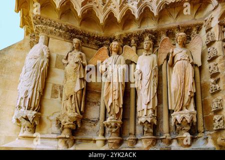 Left jamb of the left west portal with smiling angel at the cathedral with rosette and stained glass windows with depictions of kings in Reims in the Stock Photo