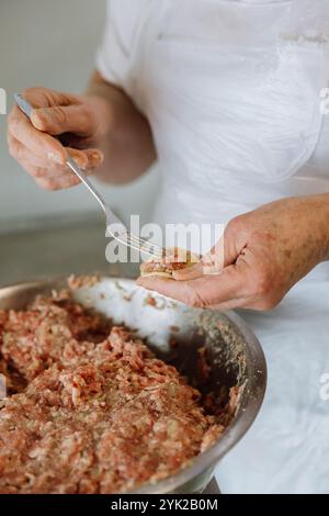 Filling a handmade dumpling with minced meat using a fork, traditional cooking process close up Stock Photo