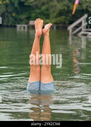 Young man doing handstand in Wörthsee, Bavaria, Germany in July 2024 Stock Photo