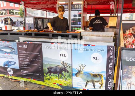 Food market stall in Bergen Norway, lady cooking offers Reindeer hot dogs and Moose burgers, takeaway food vendor,2024 Stock Photo