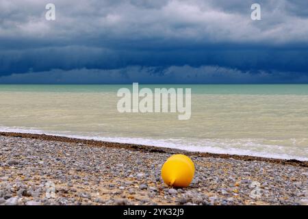 Storm clouds over the sea on the pebble beach with yellow buoy at low tide in Dieppe on the Alabaster Coast (Côte d'Albâtre, Cote d'Albatre) i Stock Photo