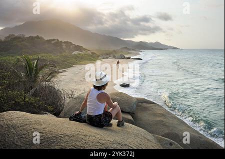 Woman sitting on a rock, admiring the beaches of Arrecifes, Tayrona National Natural Park, Department of Magdalena, Caribbean Region, Colombia, South Stock Photo