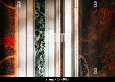 Section of a wall adorned with various marble panels. The panels showcase different colors and patterns, including green, white, red, and black hues, Stock Photo