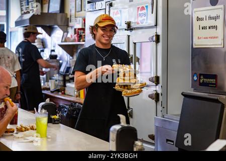 A server balances plates of hot dogs on his arm as he carries them to customers at Fort Wayne's Famous Coney Island in Fort Wayne, Indiana, USA. Stock Photo