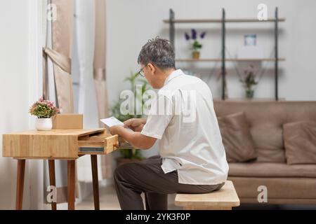 Senior old man reading documents that has forgotten in a drawer Stock Photo