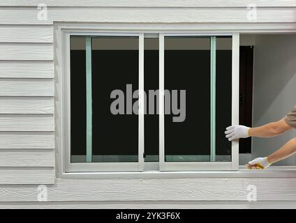 Construction worker repairing the sliding window on artificial woods siding. Stock Photo