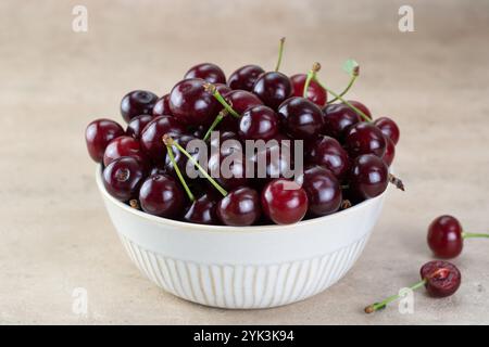 A bowl of fresh red cherries on a beige background. Fruit background Stock Photo
