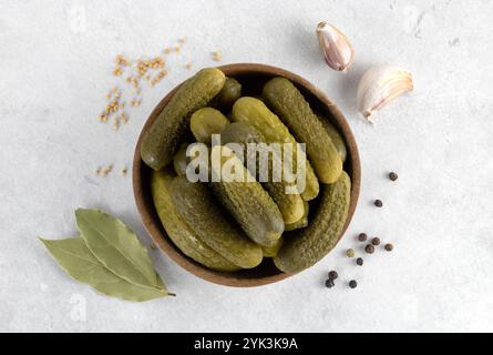 Pickled cucumbers in a wooden bowl with spices on gray background. Marinated pickled cucumbers. Top view. Stock Photo