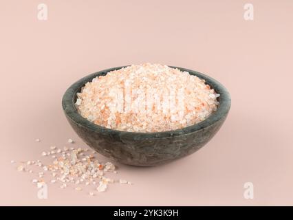 Himalayan crystalline pink salt in a gray bowl on a pink background. Spices background. Stock Photo
