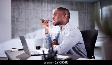 African American Using Online Time Sheets On Computer And Phone Stock Photo