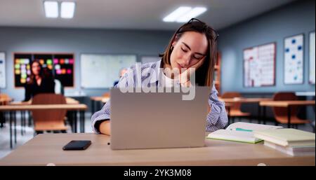 Bored Girl In Classroom Using Computer Technology. Laptop In Education Stock Photo