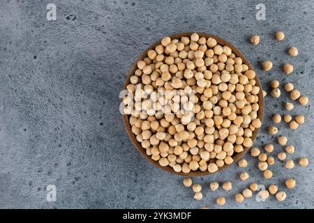 Raw or uncooked chickpeas in wooden bowl on blue background. Top view. Copy space. Superfood.  Stock Photo