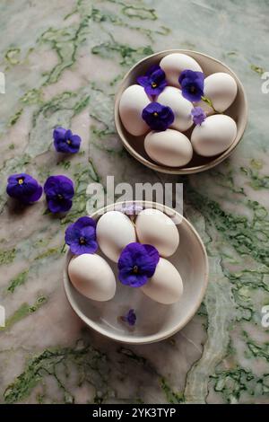 Two bowls of white eggs decorated with purple flowers Stock Photo