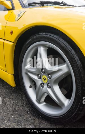 Close up detail of the alloy wheel of a giallo modena yellow Ferrari F355 Berlinetta Italian sports car produced from 1994 to 1999. Stock Photo