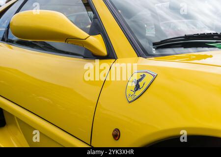 Close up detail of the right door, badge and mirror of a giallo modena yellow Ferrari F355 Berlinetta Italian sports car produced from 1994 to 1999. Stock Photo