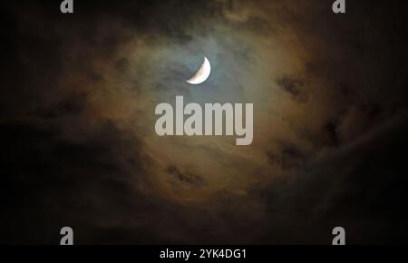 Opening through the clouds at night the moon peeking thorugh and casting a warm glow in the sky over North Carolina. Stock Photo