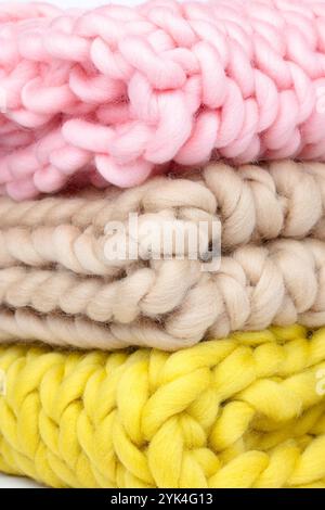 Stack of Chunky Knit Wool Blankets in Pastel Pink, Cream, and Yellow – Close-Up of Soft Braided Yarn for Crafting, Cozy Textiles, and Home Decor Ideas Stock Photo