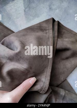 Brown leather suede fabric in hand close up, cowhide, genuine leather texture, sewing, fabric, textile, clothes store, manufacturing, apparel, fashion Stock Photo