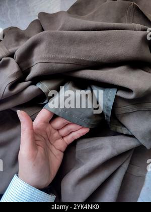 Brown leather suede fabric, lined skirt in hand, cowhide, genuine leather texture, sewing, fabric, textile, clothes store, manufacturing, apparel Stock Photo