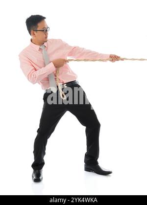 Asian businessman pulling a rope Full body Asian businessman pulling a rope , isolated on white background. Asian male model. Copyright: xZoonar.com/s Stock Photo