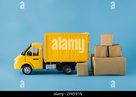 Yellow truck delivery gift box on blue background. Cargo transportation, delivery service. Transport company. Infrastructure and logistics. Unloading Stock Photo