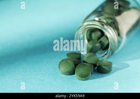 Spirulina pills in glass jars on blue background. Antioxidant nutrition. Bio-energy, biofuel, energy research. Copy space Stock Photo