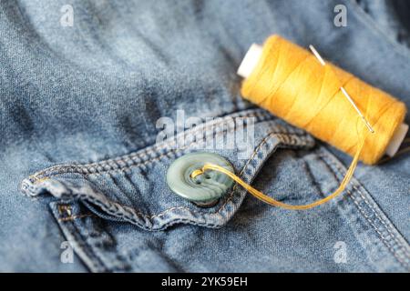 Buttons, Thread and Sewing Needle on Denim. Hand made. Close-up Stock Photo