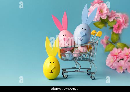 Shopping cart, Eeaster eggs bunny on blue background. Online store. Promotions. Sale concept Stock Photo