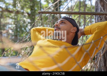 African American young man enjoying his stay at a glamping site in Europe, relaxing and napping in a hammock in beautiful nature. Stock Photo