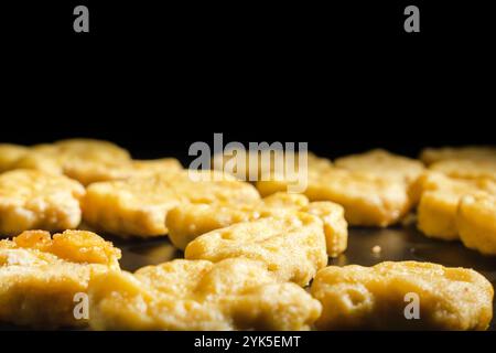 Close-up of golden fried chicken nuggets. The nuggets are arranged in a row, some of them overlap each other. Indulgence and comfort concept Stock Photo