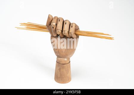 whole wheat spaghetti in a wooden hand on a white background Stock Photo