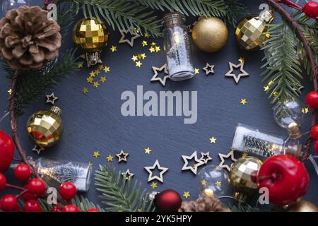 Festive frame with a place for Christmas and New Year's theme text. Sequins, stars, garland, cones, balls on a black stone background of slate. Copysp Stock Photo