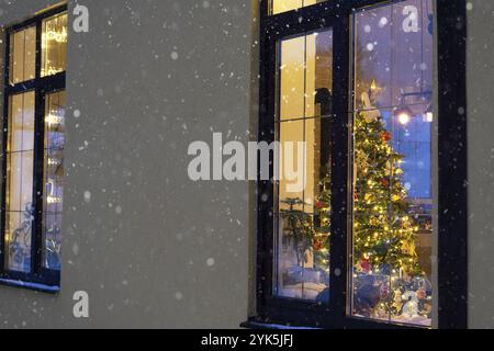 Cozy festive window of the house outside with the warm light of fairy lights garlands inside, celebrate Christmas and New Year in a warm home. Christm Stock Photo