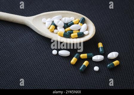 Assorted pharmaceutical medicine pills, tablets and capsules on wooden spoon Stock Photo