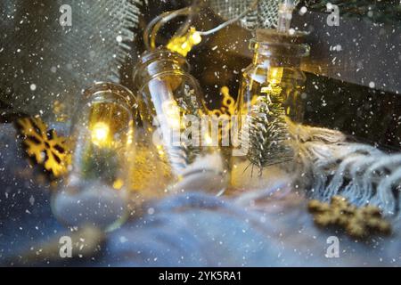 Fairy lights in a jar with a Christmas tree and snow close-up on a warm cozy plaid with wooden decor. Christmas and New Year, festive decor, comfort a Stock Photo