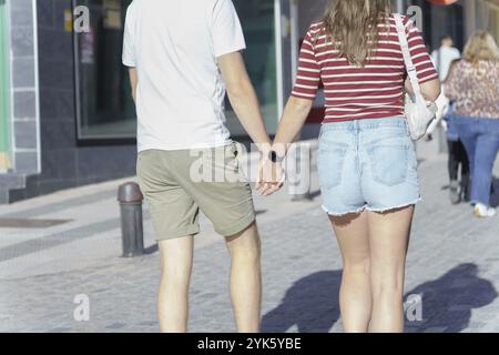 Couple strolling hand in hand along a pedestrian street Stock Photo