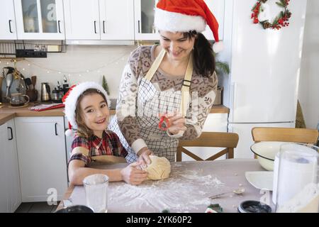 Mom and daughter in the white kitchen are preparing cookies for Christmas and new year. Family day, preparation for the holiday, learn to cook delicio Stock Photo