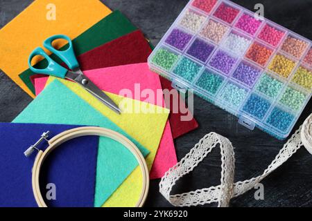 Colorful picture of craft supplies. Felt fabric, glass beads, embroidery hoop, scissors and tread on dark background. Hobby and free time concept. Stock Photo