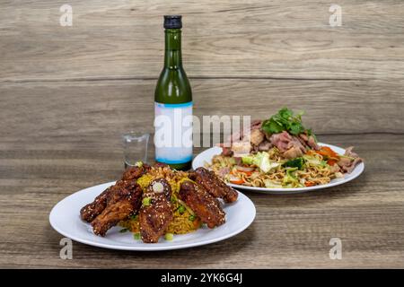Generous scoop of Vietnamese fried rice with delicious chicken wings served with chow mein and a cold bottle of sake. Stock Photo