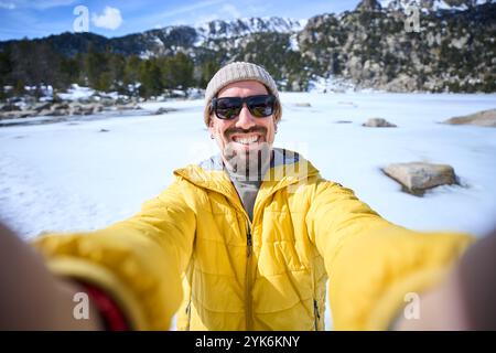 POV of happy Caucasian young bearded man taking selfie with two hands with mobile in snowy mountains Stock Photo